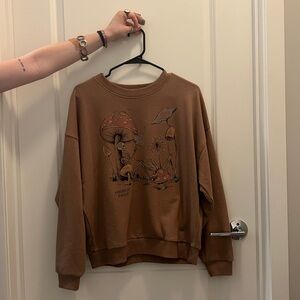 Light brown American Eagle crewneck with mushroom and skeleton graphic, size M